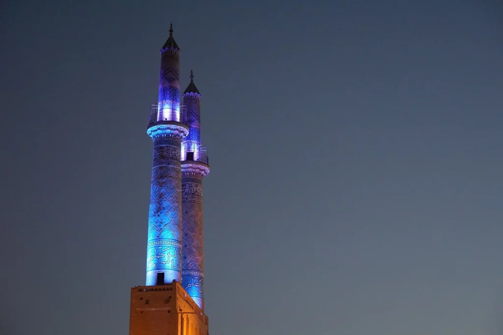 مئذنة مسجد مضاءة ليلاً بخط كوفي على جدارها